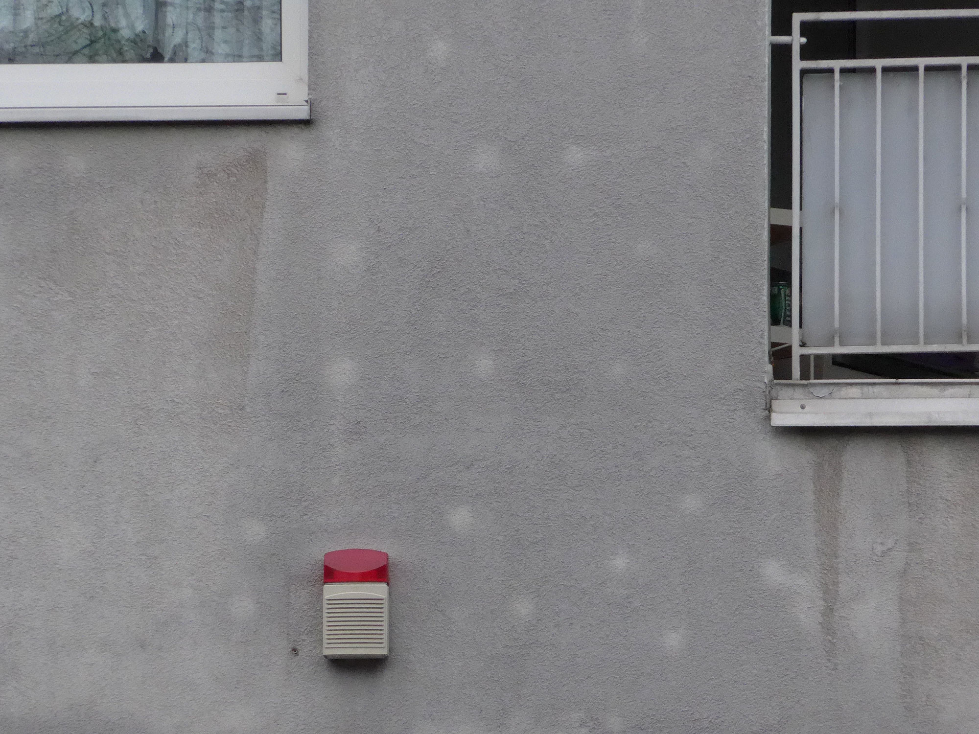 Verputzte WDVS-Fassade, auf der sich die Dübel als helle Flecken abzeichnen