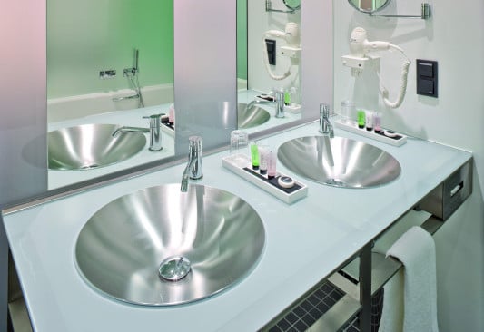 Die Waschtische aus rückseitig lackiertem Glas mit bündig eingelassenen Becken aus Edelstahl wurden speziell für das Hotel angefertigt