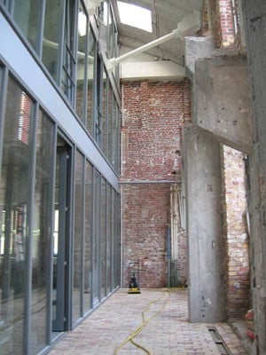 Eine zweite Schale bildet die hinter die Backsteinmauern eingestellte Holz-Glas-Fassade