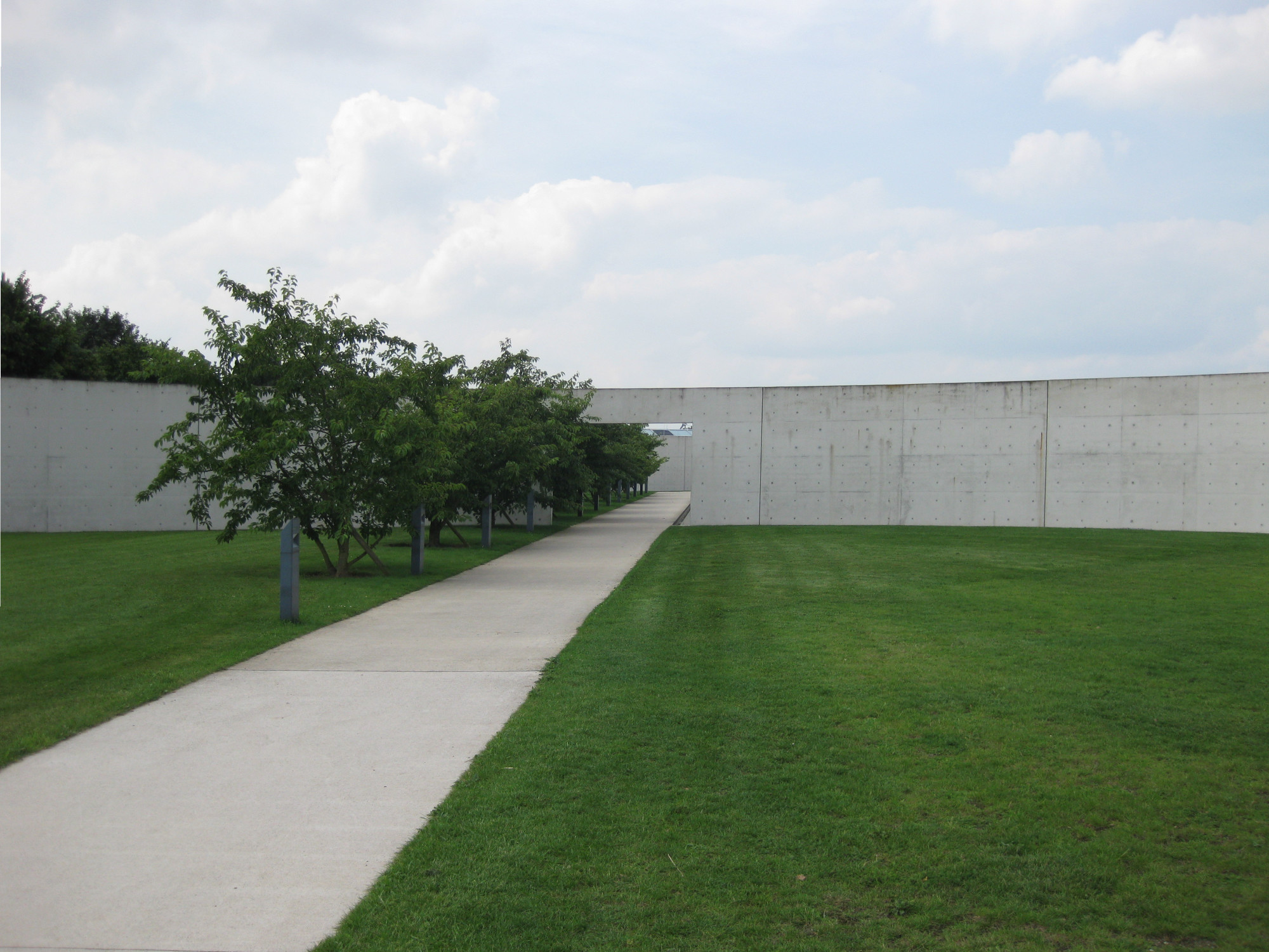 Erschlossen wird das Museum durch ein Portal, das von einer gebogenen Wand geformt wird, und entlang einer Reihe von Kirschbäumen.