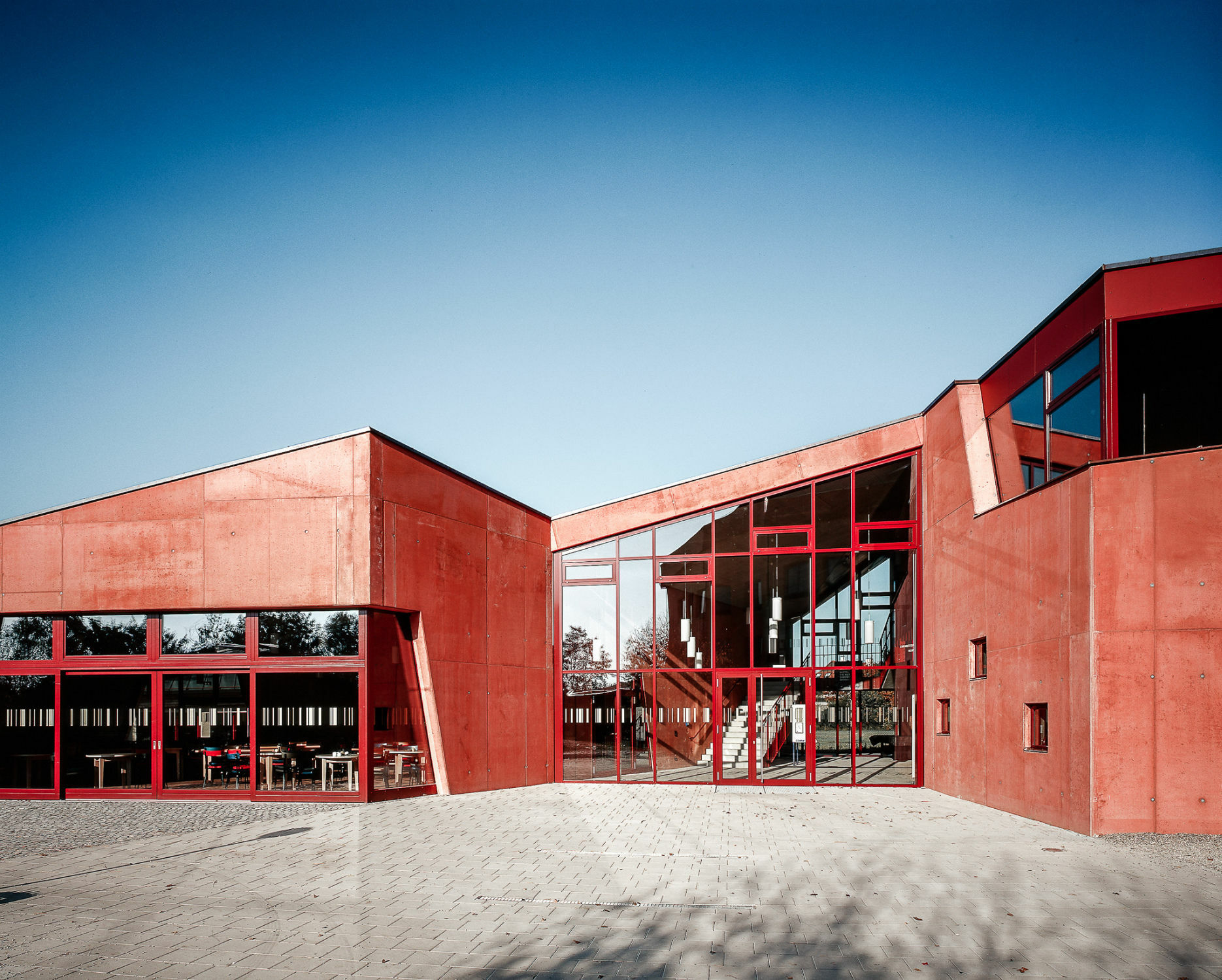 Die Außenhülle der Schule besteht aus rot eingefärbtem Beton mit naturbelassener Oberfläche.