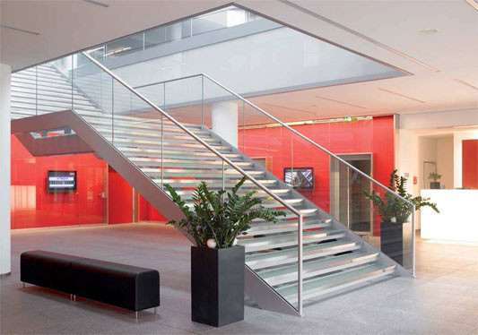Eine gläserne Treppe verbindet die Eingangshalle mit den oberen Geschossen.