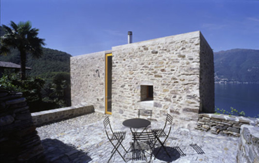 Über die oberste Ebene wird das Ferienhaus erschlossen; die hochformatige Eingangstür erscheint wie ein Schlitz im sonst geschlossenen Mauerwerk