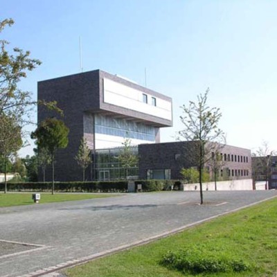 Zwei einander gegenüber liegende Riegel unterschiedlicher Höhe sind durch eine gläserne Erschließungshalle verbunden