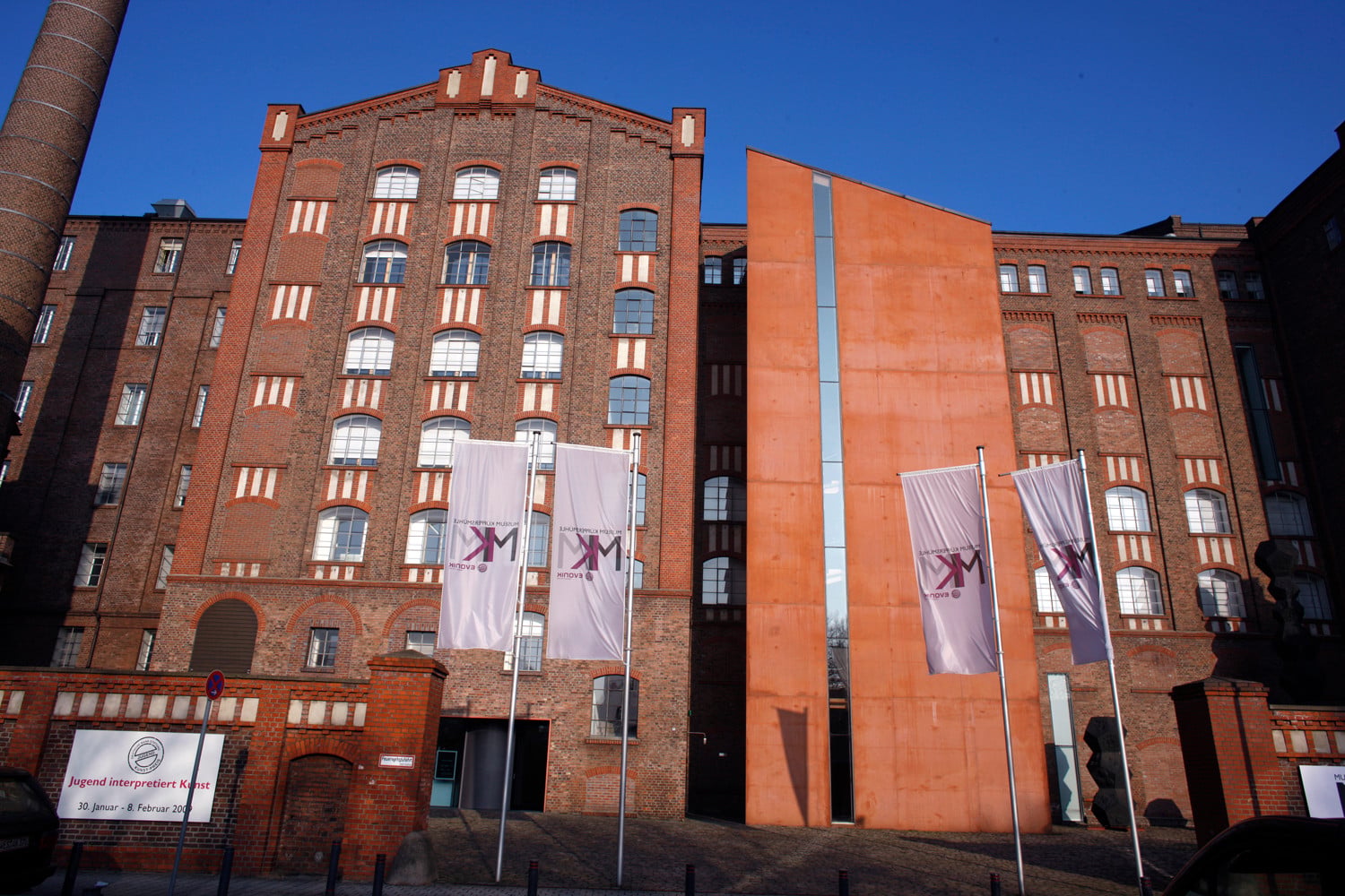 Südfassade mit dem Ergänzungsbau aus ziegelrotem Sichtbeton, der das Treppenhaus aufnimmt