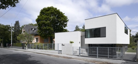 Drei Baukörper verschiedener Größe mit unterschiedlich geneigten Dächern sind verbunden über einen niedrigeren Riegel.