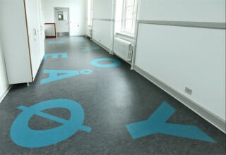 In einer Grundschule im dänischen Vanloese von Kant Architects und Dorte Mandrup Architects bedecken großflächige Intarsien aus Marmorette-Linoleum die Flurböden.