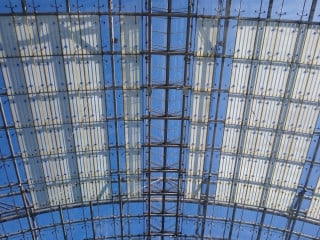Wesentliche Eigenschaft von Glas ist die Lichtdurchlässigkeit – allerdings nur für einen Teil des Lichtspektrums (im Bild: Punktgelagerte Überkopfverglasung der Neuen Messe Leipzig; gmp Architekten, 1996).