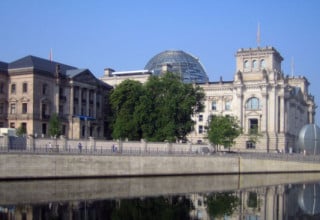 Links das Reichstagspräsidentenpalais, dahinter das Reichstagsgebäude, im Vordergrund die Spree