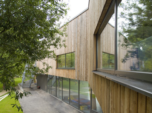 Die Fassade im Obergeschoss besteht aus Lärchenholzplanken, die im Ergeschoss ist großflächig verglast
