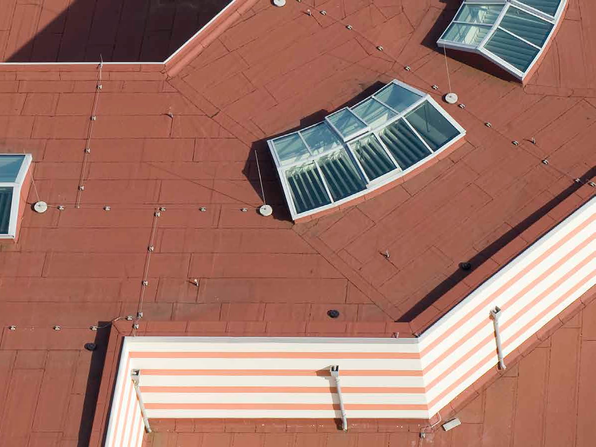 Die Flachdächer dieses Gebäudes sind mit rot beschieferten Bitumenbahnen abgedichtet.