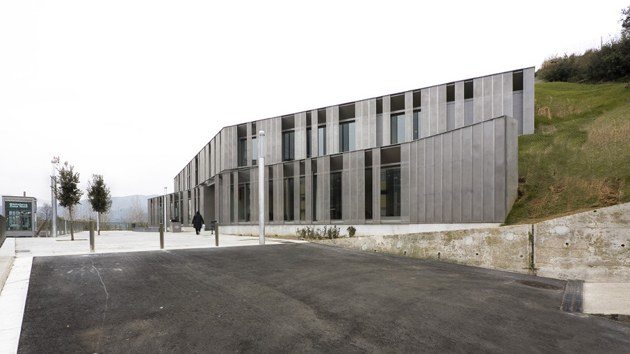 Eine Auffahrt entlang der abfangenden Stützwände aus Beton führt zum Vorplatz der Bibliothek