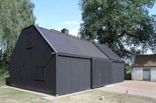 Um die monochrome Gebäudehülle zu erzielen, wurde die Holzfassade dunkel gestrichen