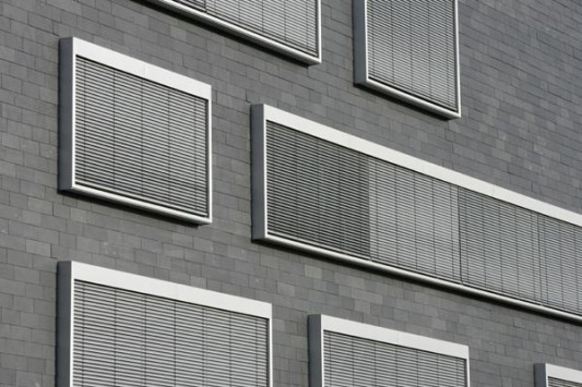 Fassadenausschnitt mit Aluminiumfensterrahmen und integriertem Sonnenschutz