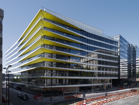 Eine Glas-Aluminium Fassadenkonstruktion mit Balkonen umschließt das Gebäude