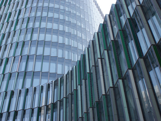 Aus der geschwungenen Fassade ragen in regelmäßigen Abständen Schuppen hervor